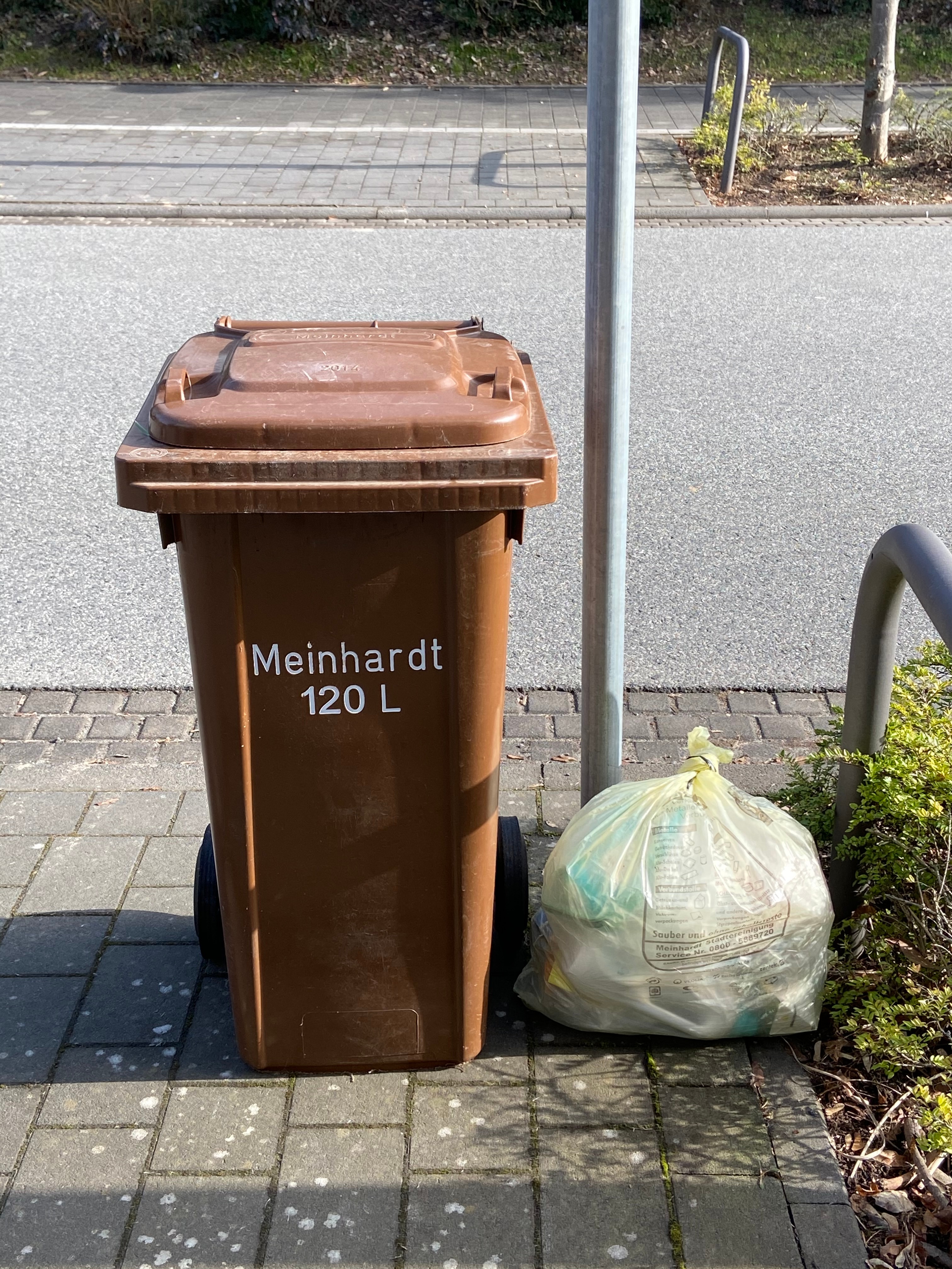 Links steht eine Mülltonne und rechts ein Müllsack