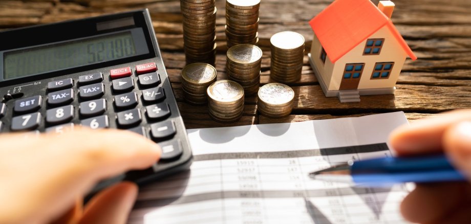 Grundsteuer Ein Mann errechnet die Höhe der Grundsteuer für ein Haus
