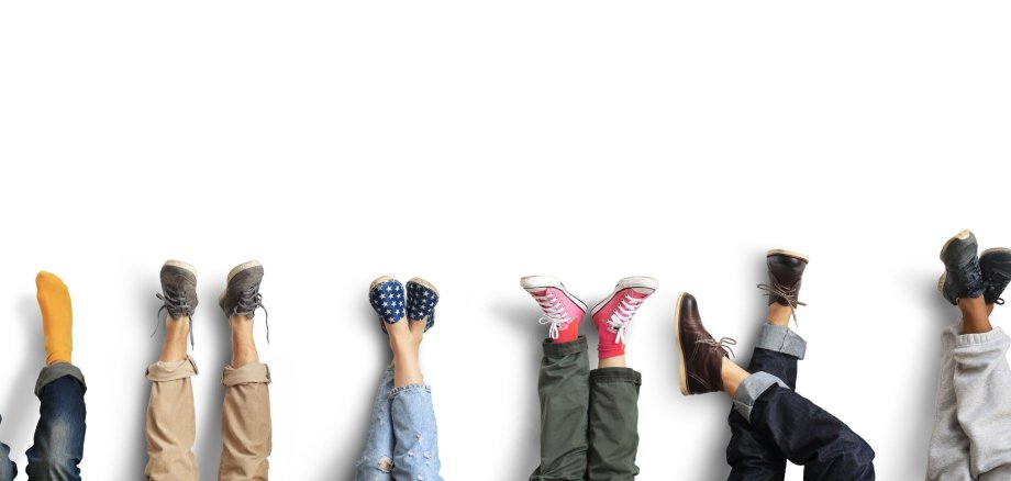 Viele verschiedene, gekleidete Beine und Füße, die ausgestreckt in der Luft sind