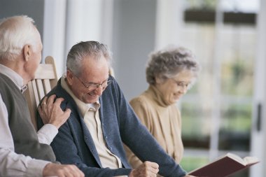 Senioren Drei Senioren, die sitzen und sich unterhalten. Im Hintergrund liest jemand.