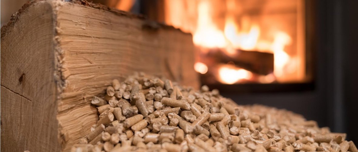 Holzpellets zum Heizen Holzpellets und ein Kaminfeuer im Hintergrund