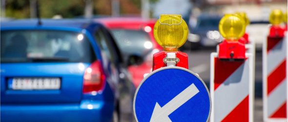 Baustellenschilder, die die Autofahrer auf der linken Fahrbahn halten