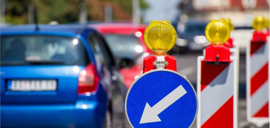 Baustellenschilder, die die Autofahrer auf der linken Fahrbahn halten