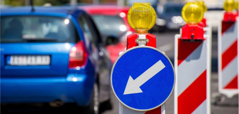 Baustellenschilder, die die Autofahrer auf der linken Fahrbahn halten