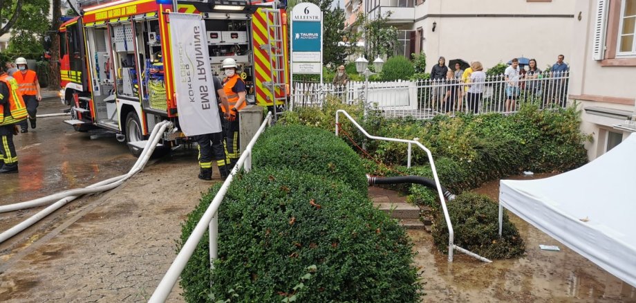 Feuerwehrauto steht an Geschäften und pumpt das Wasser ab