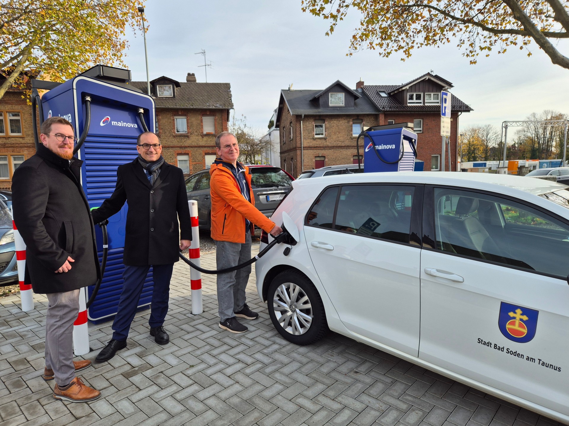 Mainova-Schnellladesäule Kevin Bornath, Mainova-Kommunalmanager, Bürgermeister Dr. Frank Blasch und Detlef Schümann, Klimaschutzbeauftragter der Stadt, (v.l.n.r.) bei einem Vororttermin an den neuen Schnellladesäulen.