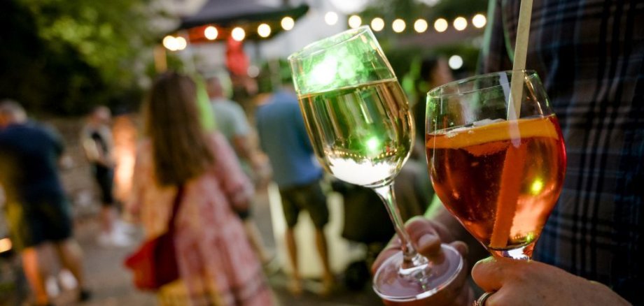 Zwei Weingläser mit Menschen im Hintergrund beim Feiern des Sommernachtsfests im Alten Kurpark